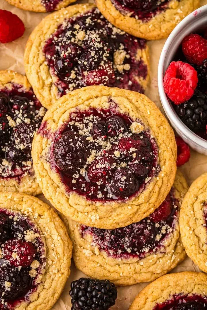 Delicious berry cobbler cookie on a plate, topped with fresh berries and ice cream.