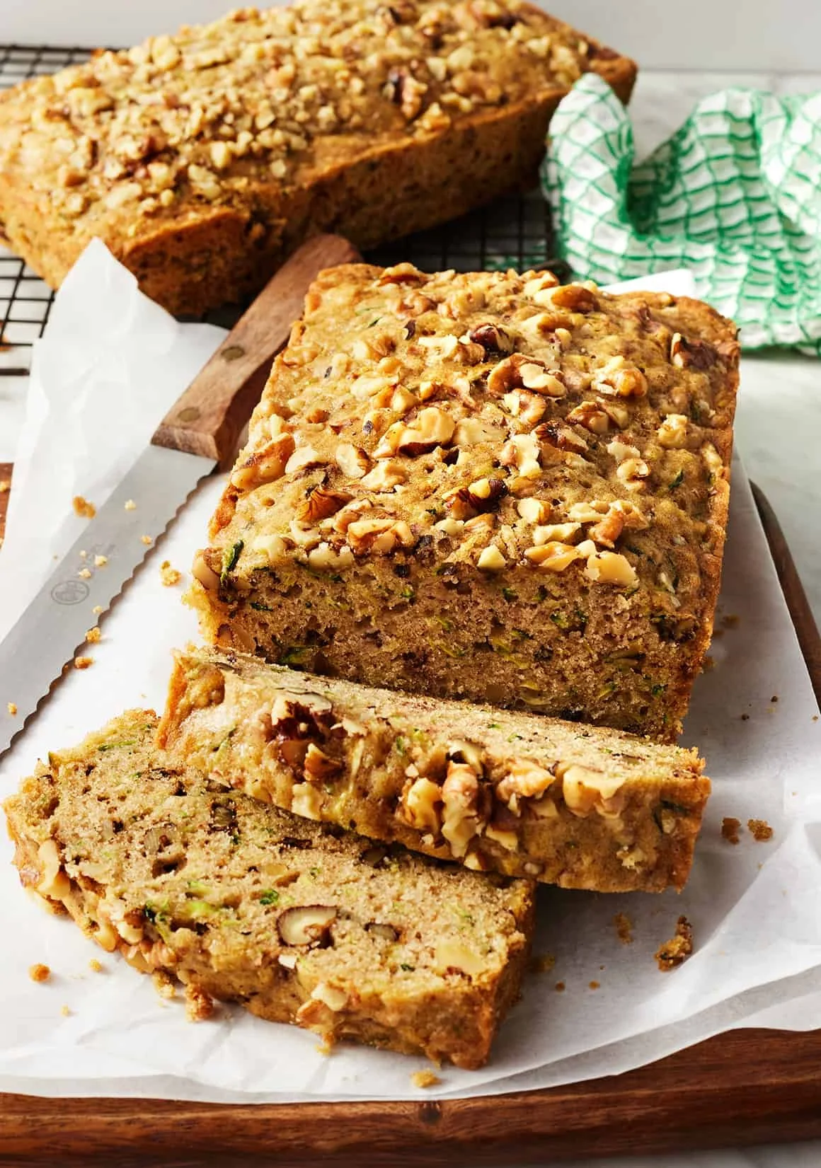 Loaf of freshly baked zucchini bread with slices on a wooden cutting board.