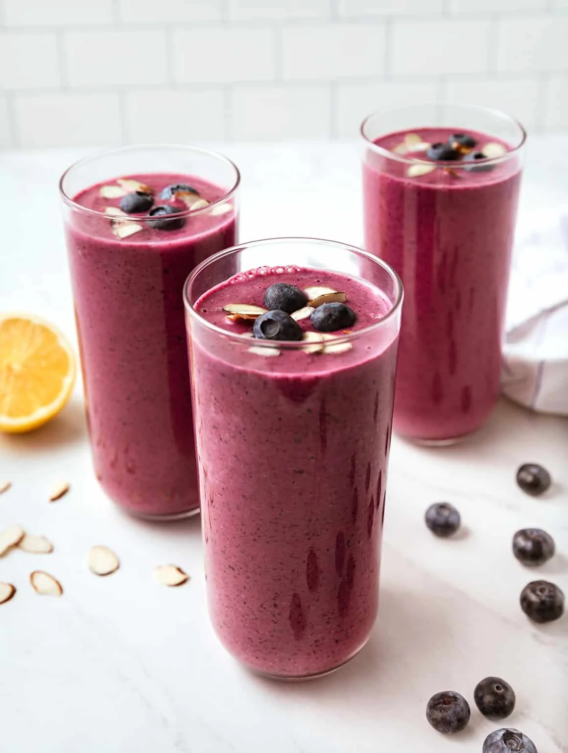 A vibrant blueberry smoothie in a glass, topped with fresh blueberries and mint.