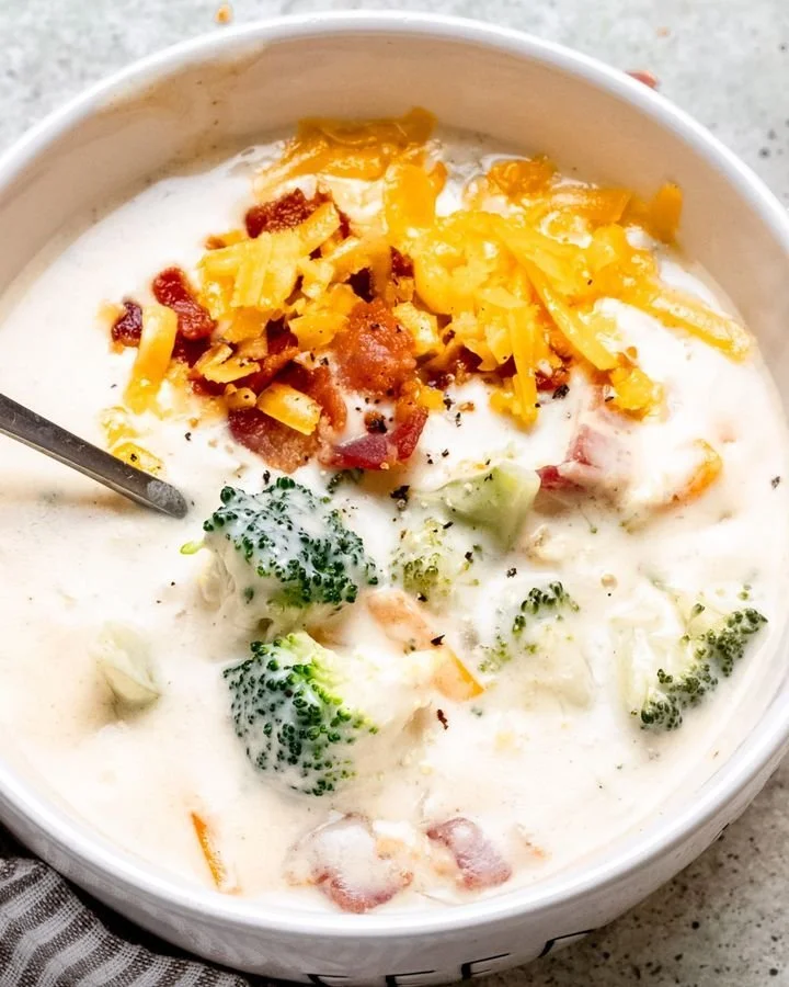 Bowl of delicious broccoli cheese soup garnished with cheese and broccoli florets.