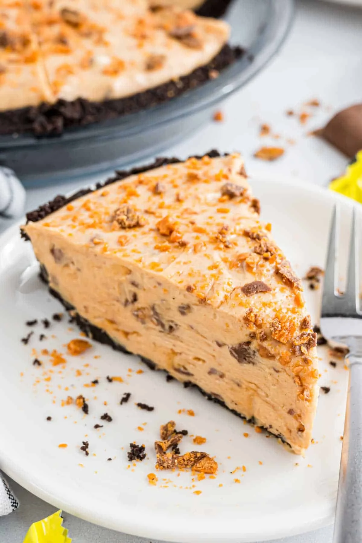 Delicious slice of Butterfinger Pie with whipped cream and chocolate drizzle