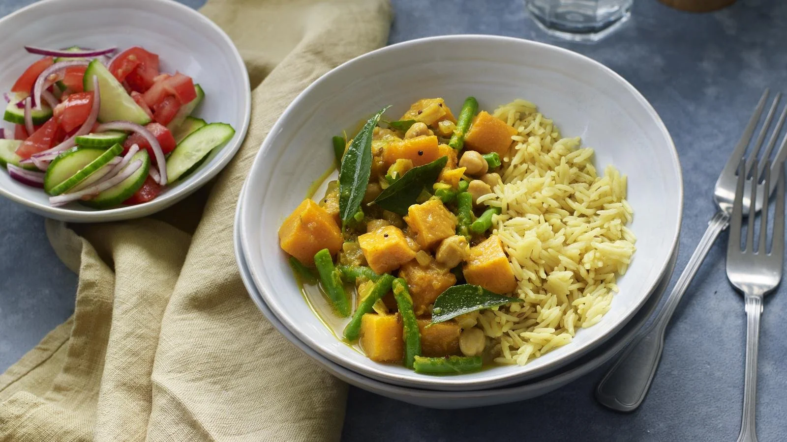 A bowl of creamy butternut squash curry garnished with cilantro and served with rice.