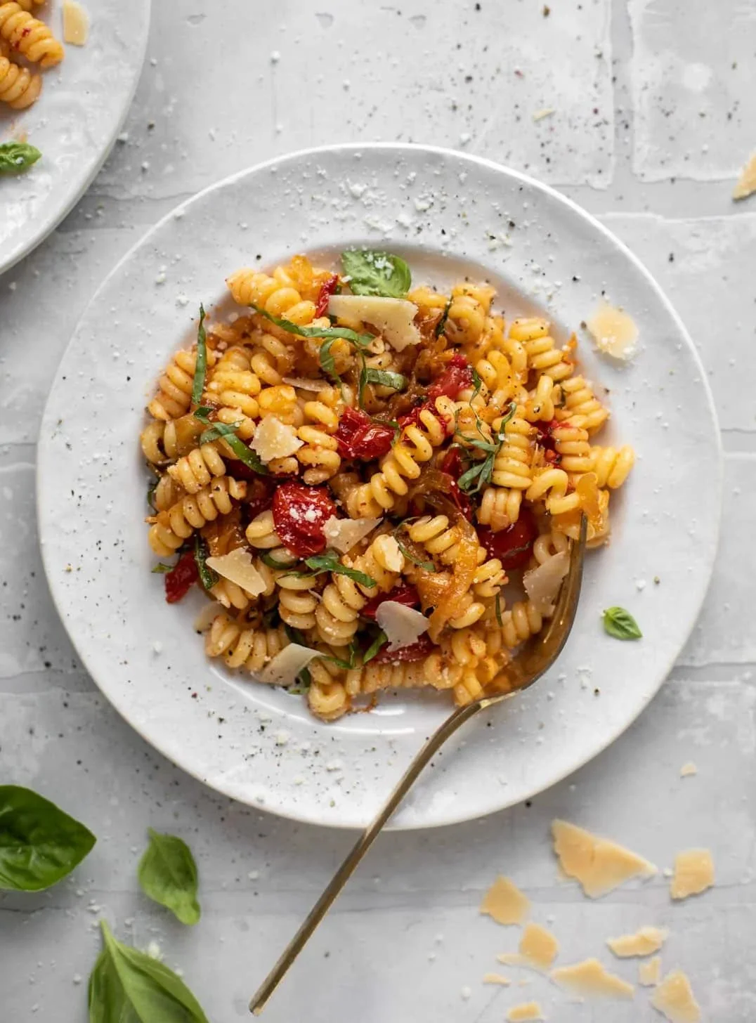 Caramelized onion and burst cherry tomato pasta served in a bowl.