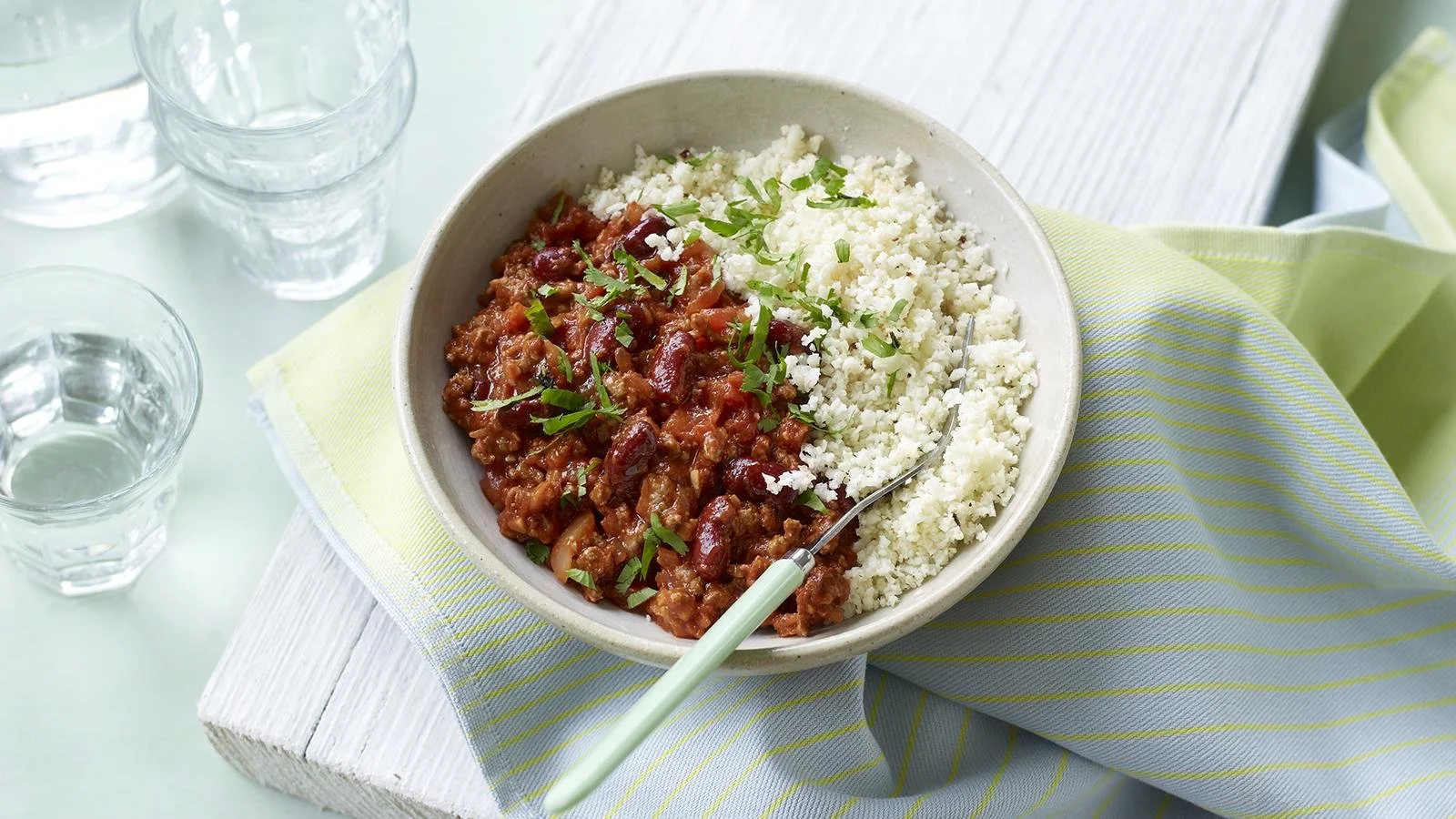 Bowl of Chili Con Carne served with cauliflower rice, garnished with fresh cilantro
