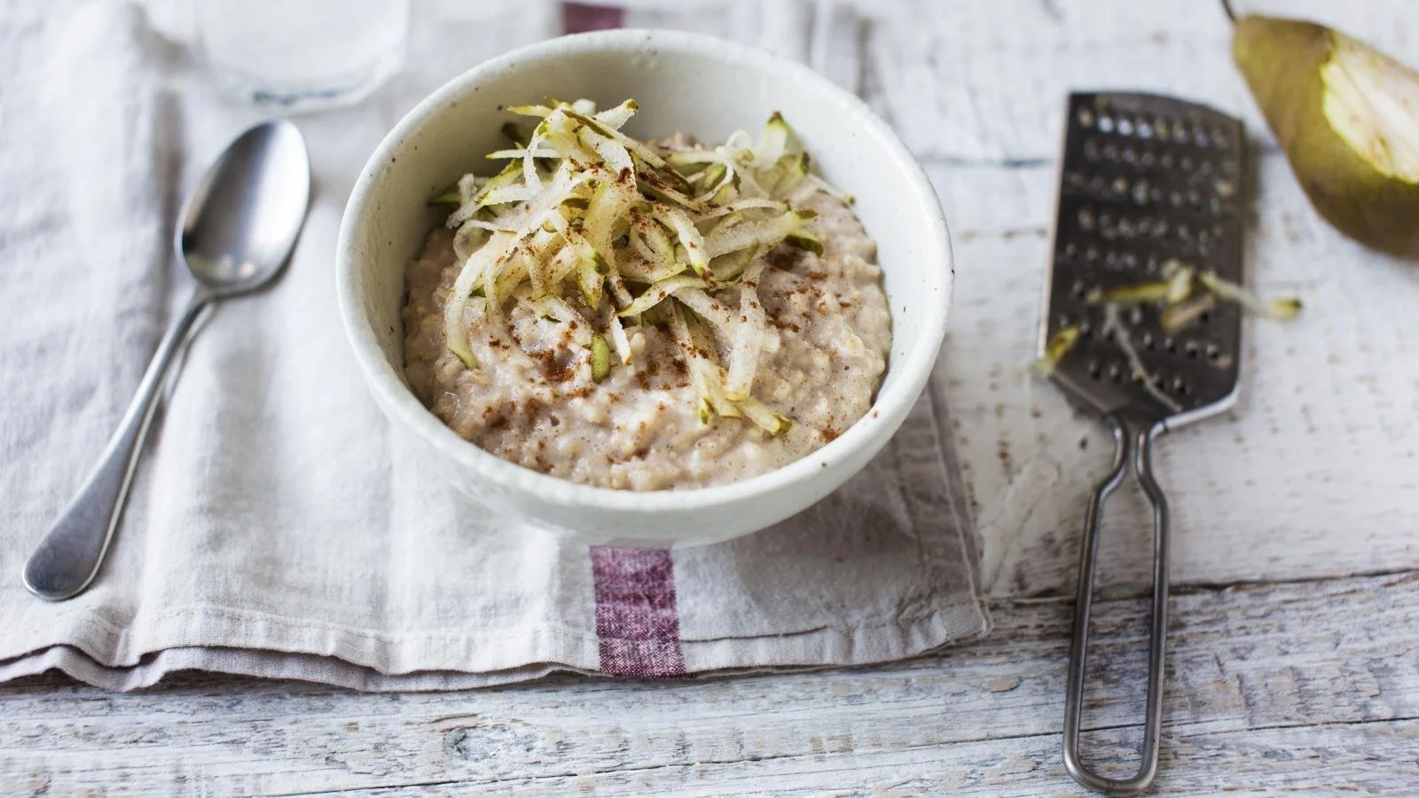 Delicious cinnamon porridge topped with fresh pear slices in a bowl.