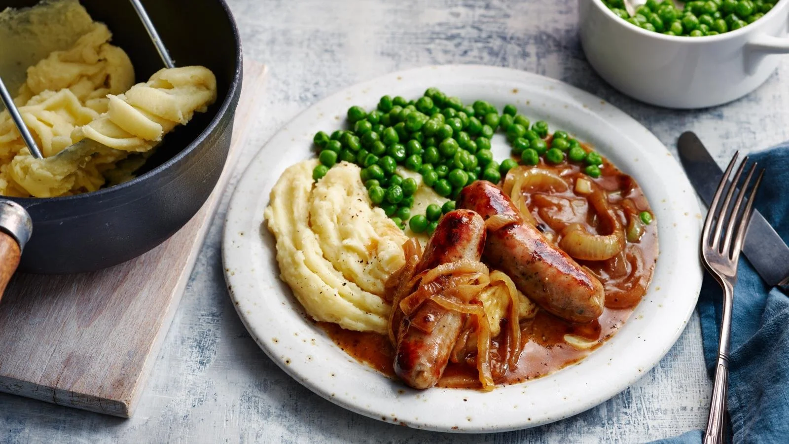 Plate of classic sausage and mash with gravy and peas