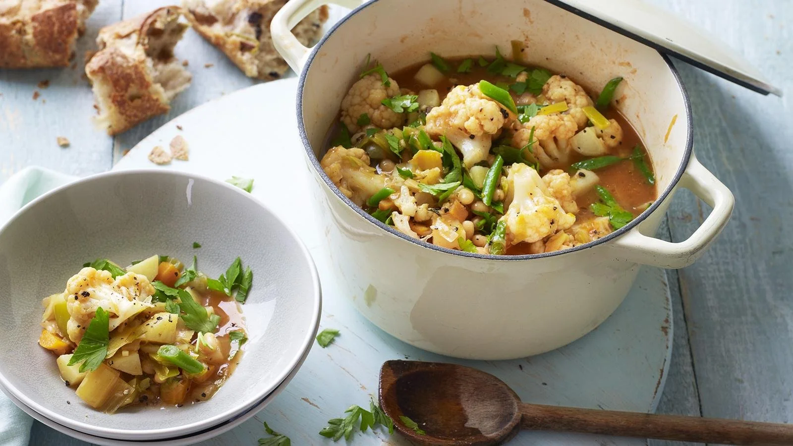 A bowl of cozy vegetable stew filled with colorful vegetables and herbs.