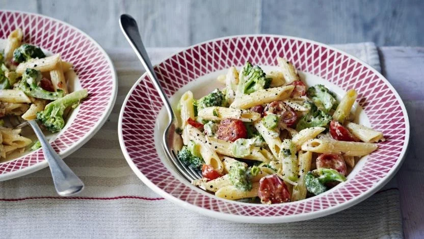 Creamy broccoli pasta dish garnished with herbs