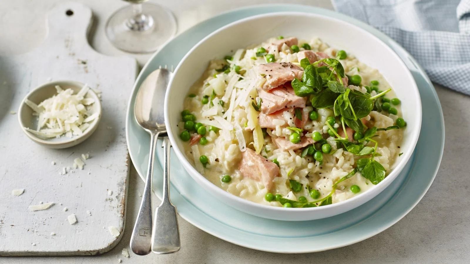 Plate of creamy salmon, fennel, and pea risotto garnished with herbs