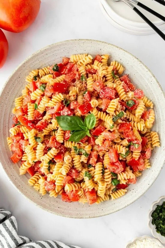 Fresh tomato pasta dish garnished with basil and Parmesan cheese