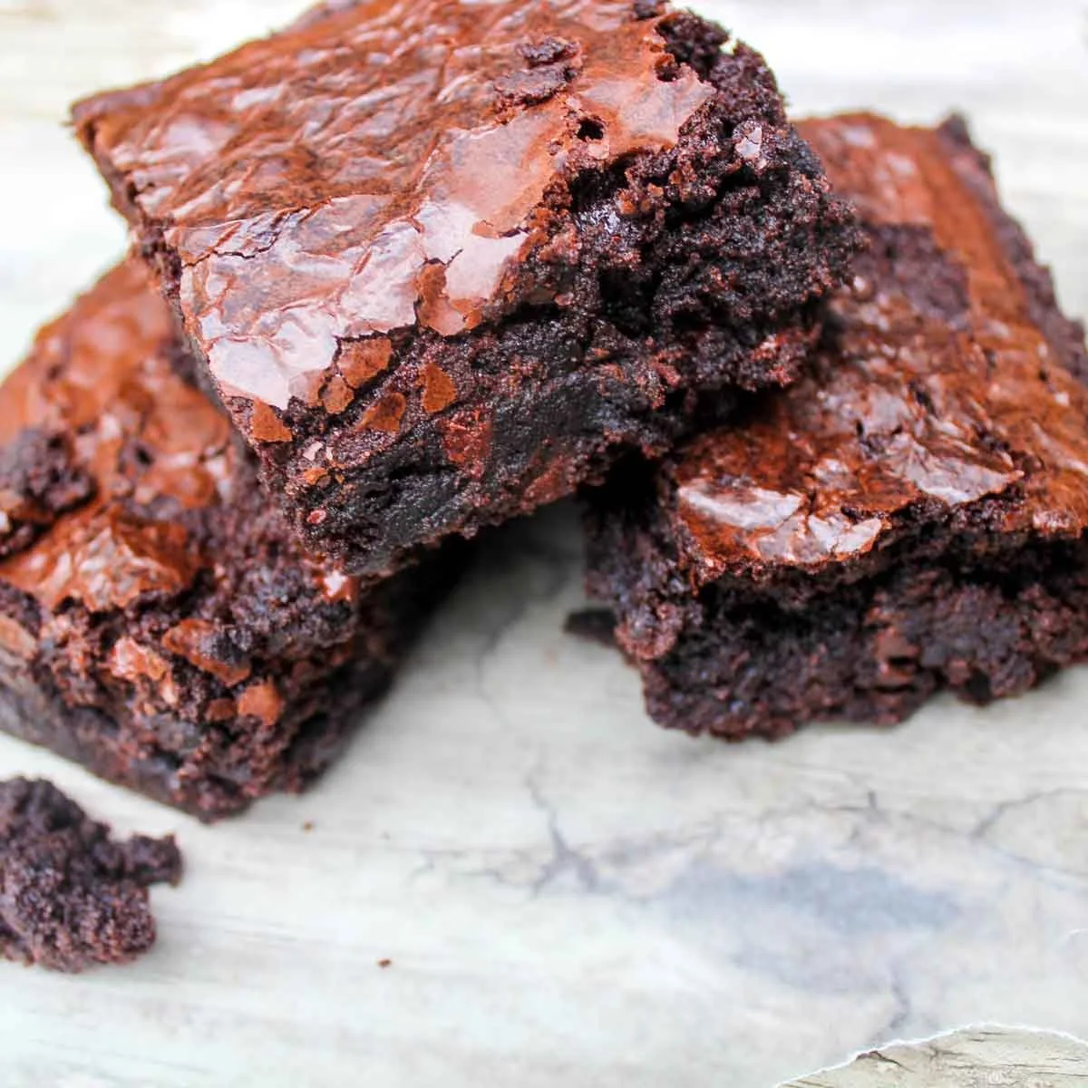 Fudgy chocolate coconut brownies on a plate, topped with coconut flakes.
