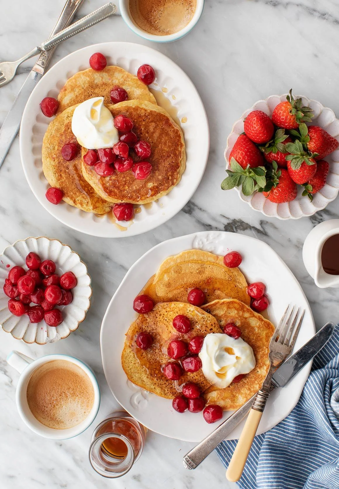 Fluffy gluten-free pancakes stacked on a plate with syrup and berries.
