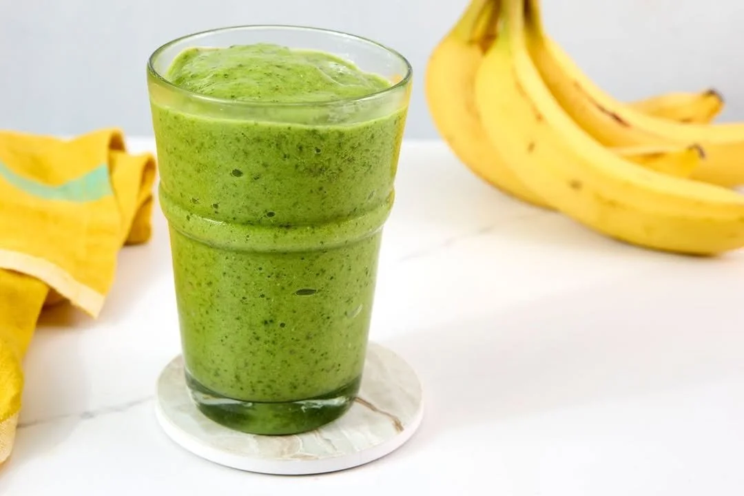 A refreshing green smoothie made with spinach, banana, and almond milk in a glass.