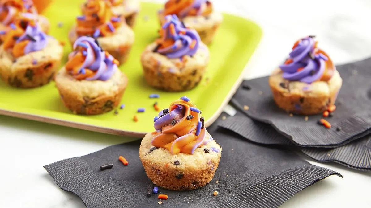 A tray of decorated Halloween Cookie Cups featuring pumpkin and ghost designs.