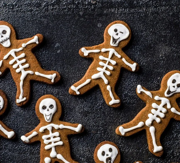 Decorated Halloween skeleton gingerbread men cookies on a spooky background.