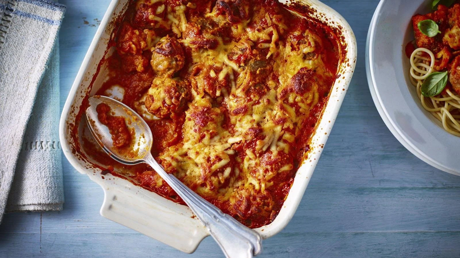 Healthy meatball bake fresh out of the oven, topped with herbs and sauce.