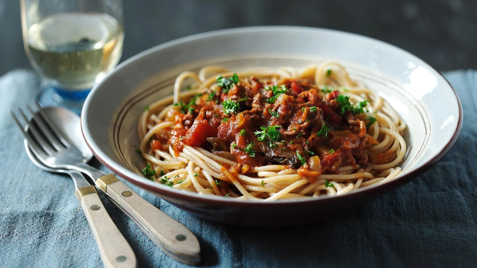 Healthy spaghetti bolognese dish served with fresh herbs and ingredients