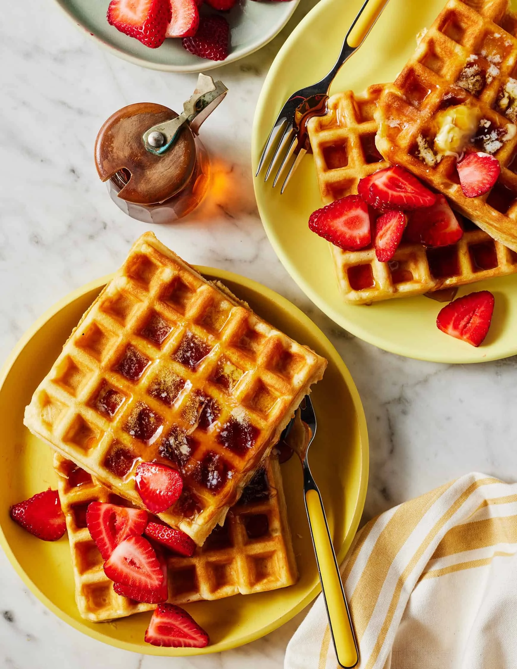 Stack of homemade waffles topped with syrup and berries