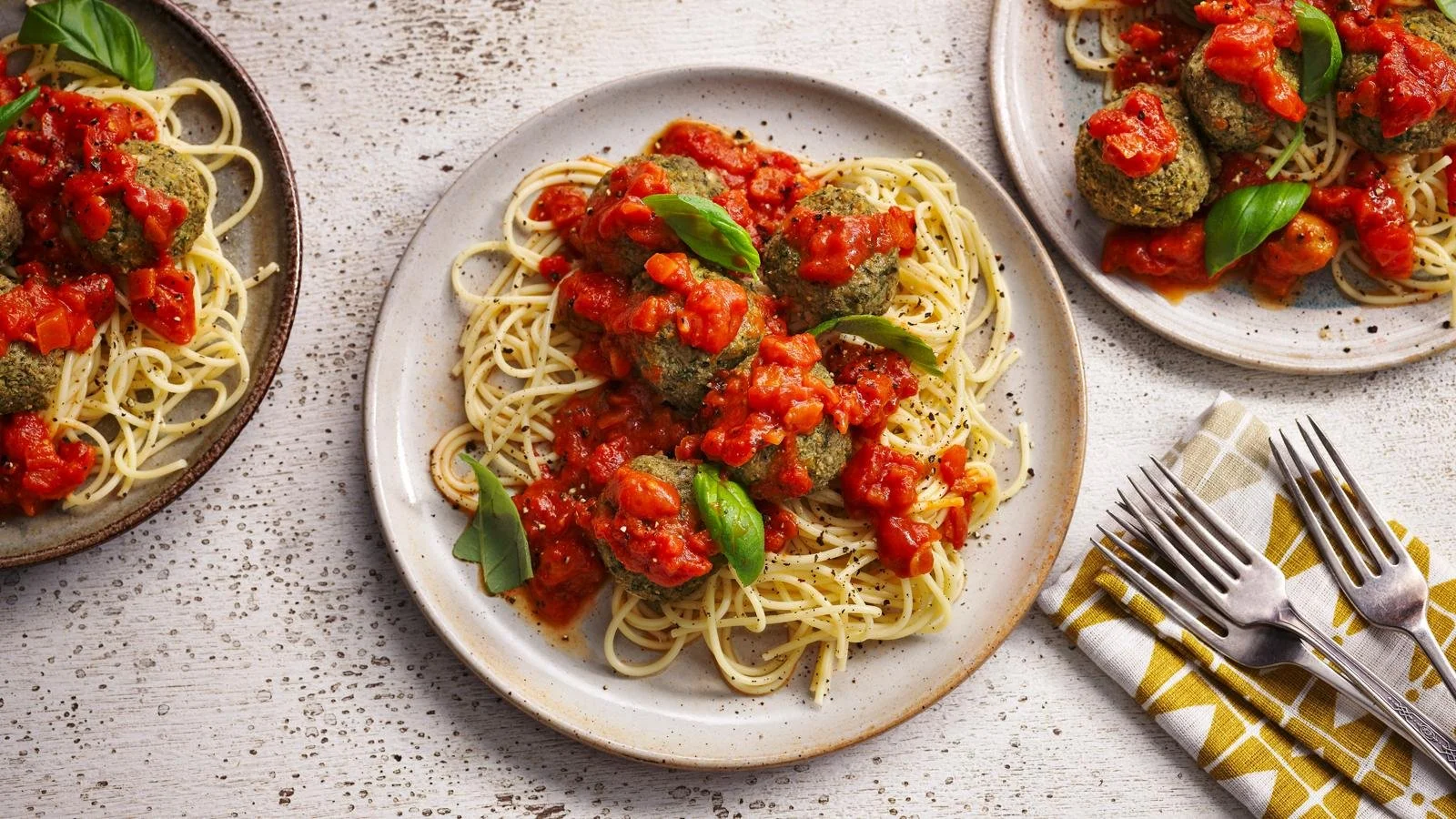 Plate of Italian veggie balls with spaghetti, garnished with fresh herbs.