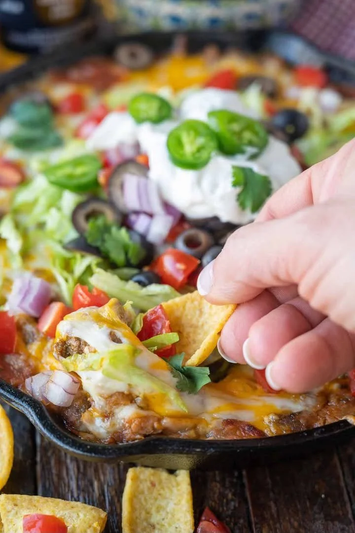 Loaded taco dip garnished with fresh toppings and served in a bowl