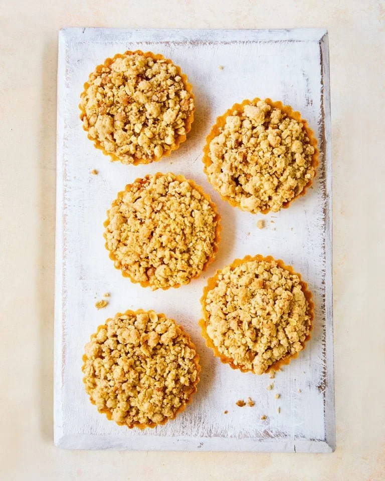 Mini apple crumble pies with a golden topping and apple filling.