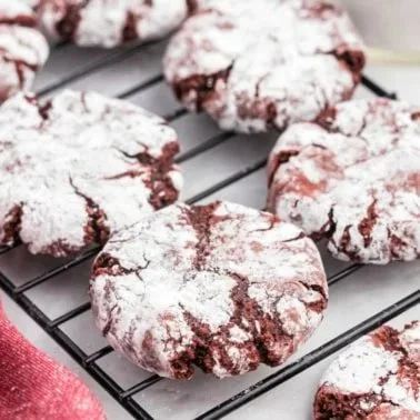 Freshly baked Red Velvet Crinkle Cookies with a rich red hue and powdered sugar coating