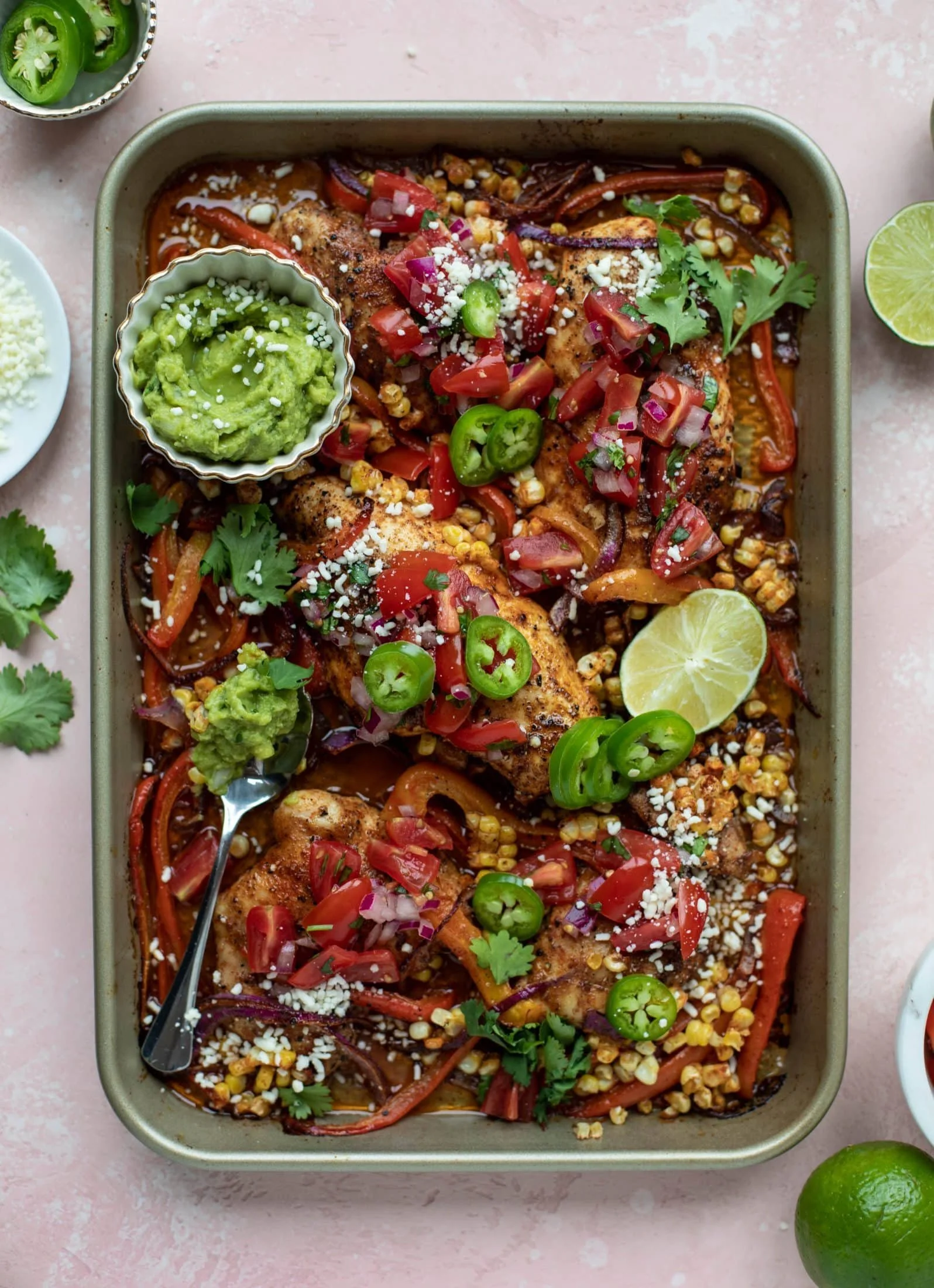 Sheet pan nacho chicken topped with cheese and jalapeños