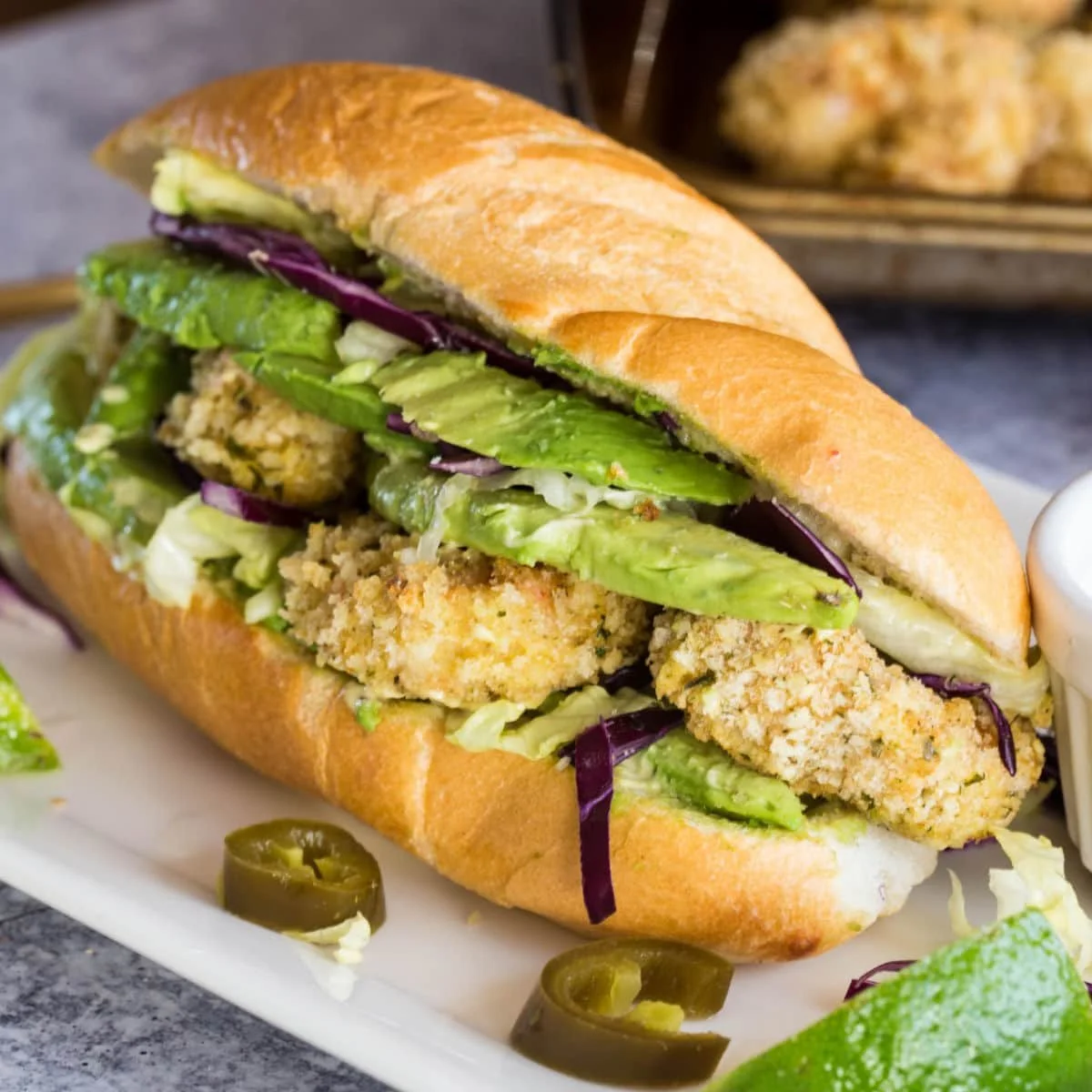 Shrimp Po' Boy sandwich with avocado remoulade on a rustic wooden table