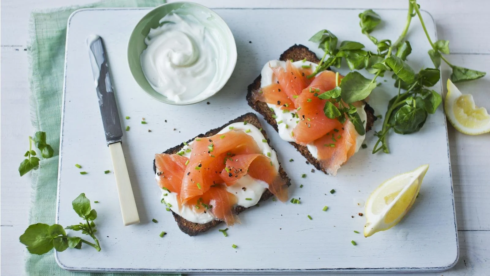 Smoked salmon open-sandwich topped with fresh herbs and vegetables