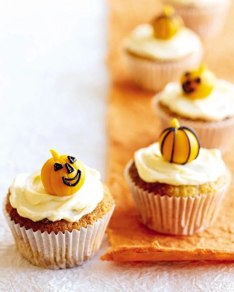 Spiced pumpkin muffins with cream cheese icing on a wooden table