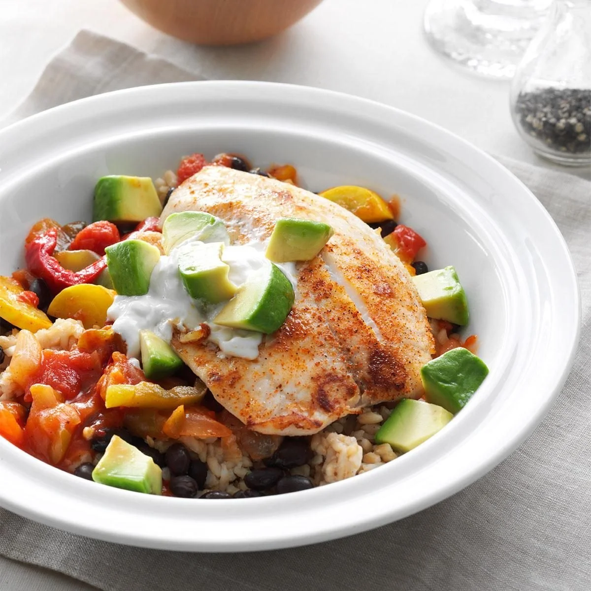 Spicy Tilapia Rice Bowl topped with fresh vegetables and herbs