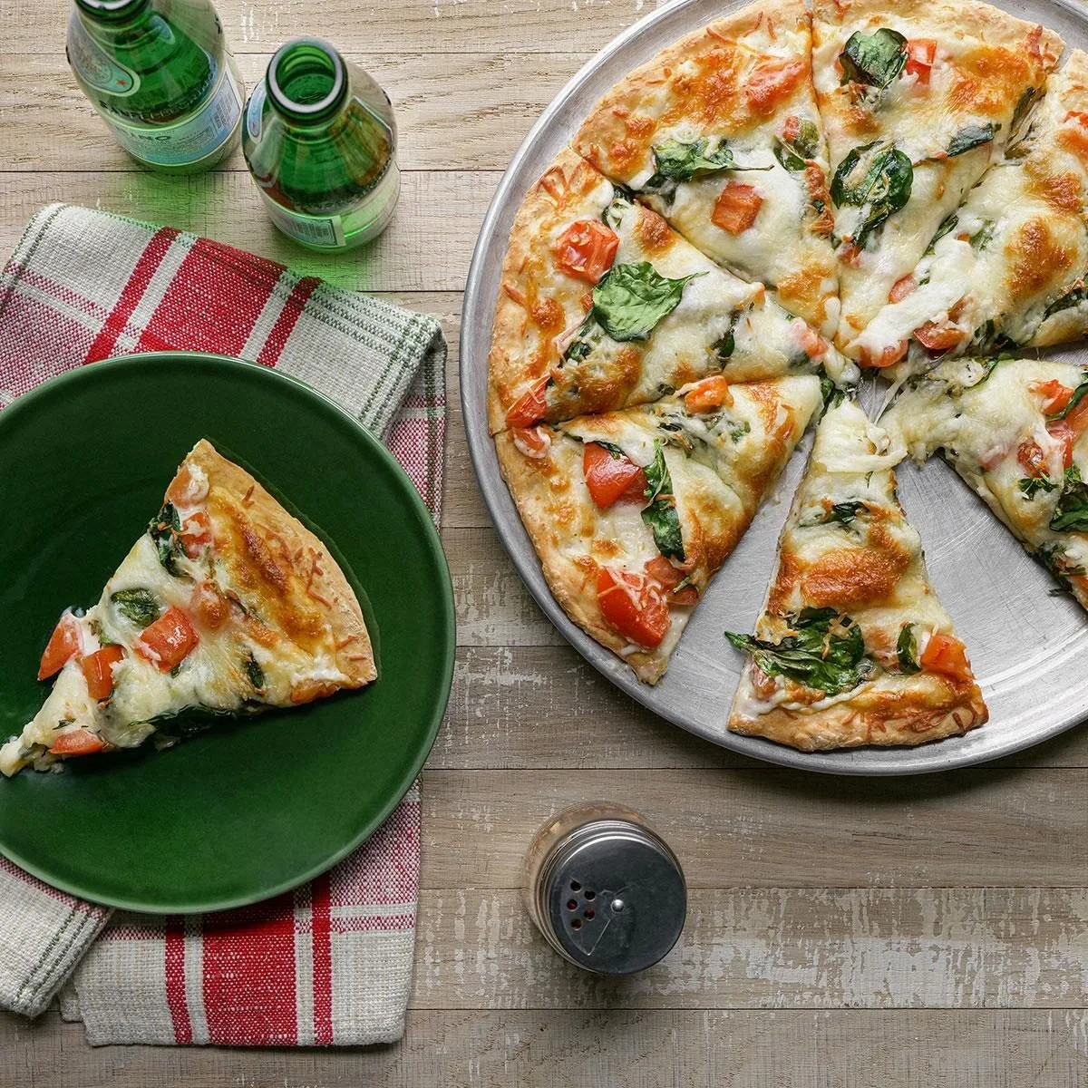 Delicious homemade Spinach Pizza topped with cheese and fresh spinach leaves