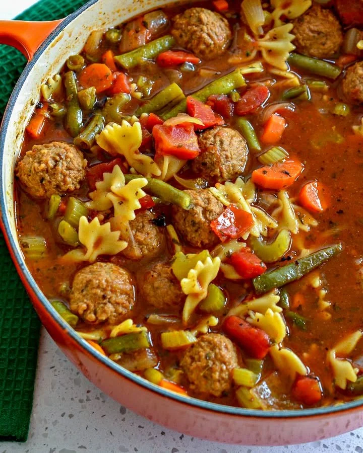 A bowl of tender meatball soup with fresh herbs and vegetables