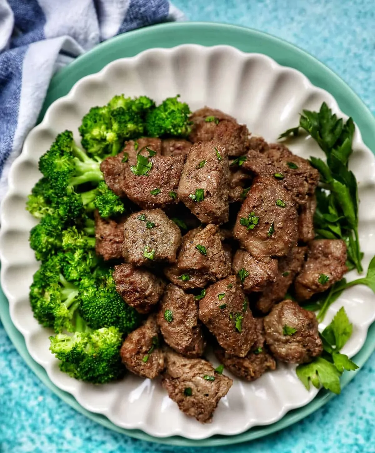 Delicious air fryer steak tips garnished with herbs and served on a plate.