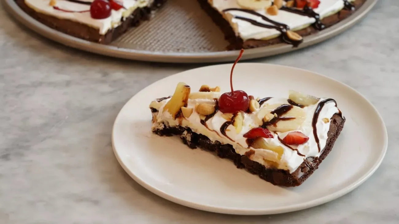 Delicious Banana Split-Brownie Pizza topped with bananas, cherries, and whipped cream.