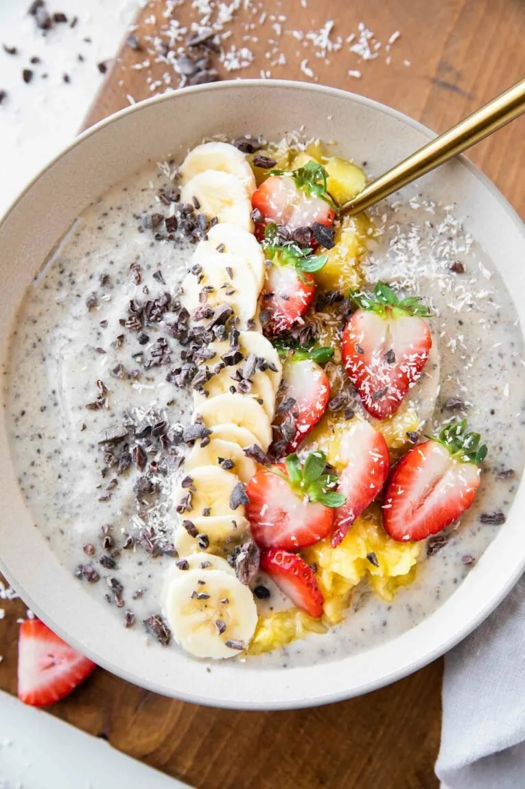 Colorful banana split smoothie bowl topped with fruits and nuts