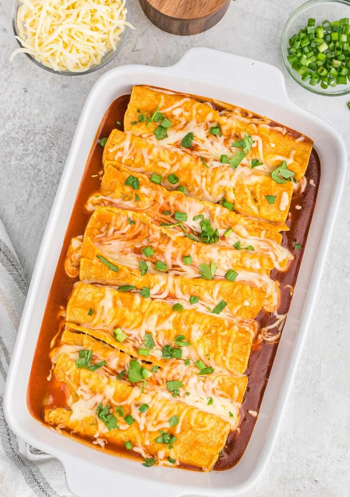 Plate of homemade Bean and Cheese Enchiladas topped with sauce and garnished.