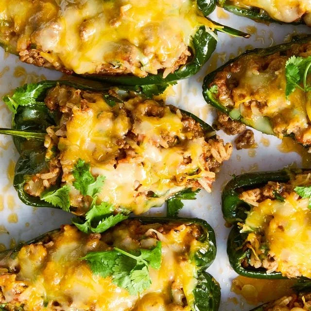 Beef and rice stuffed poblano peppers on a plate, garnished and ready to serve.
