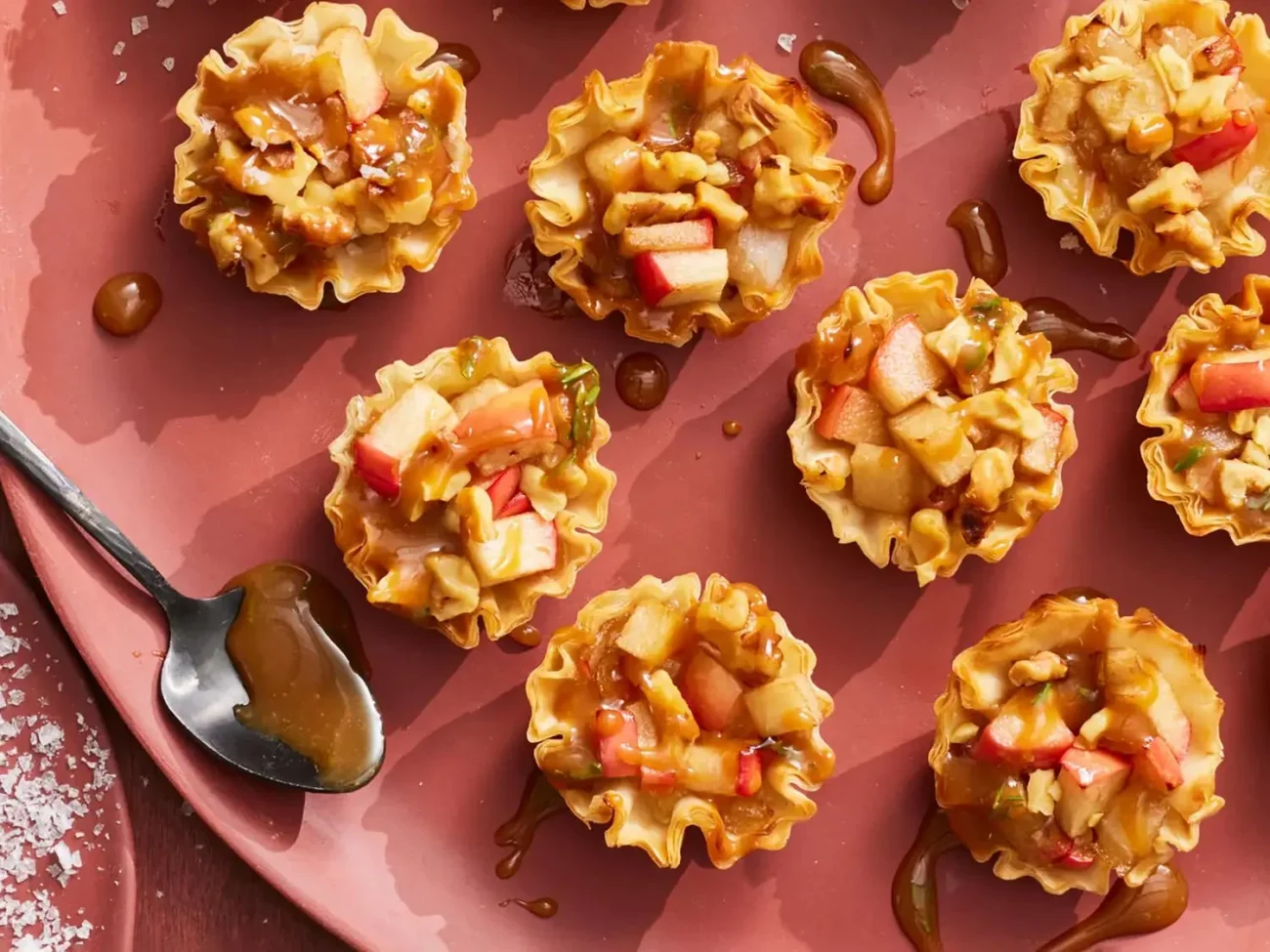 Brie and apple mini tarts topped with thyme caramel on a wooden board