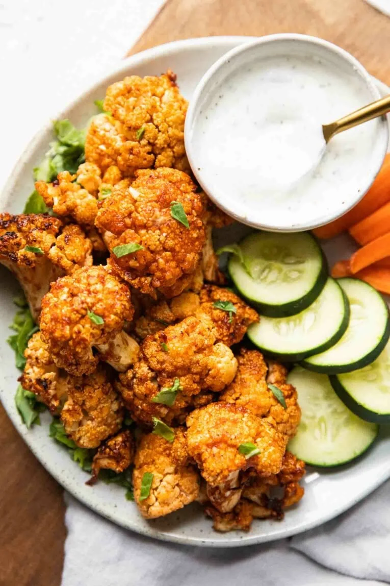 Delicious Buffalo Cauliflower served on a plate topped with sauce and garnishes