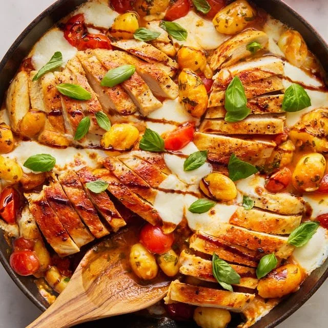 Delicious Caprese Chicken Gnocchi Skillet topped with fresh basil and mozzarella.