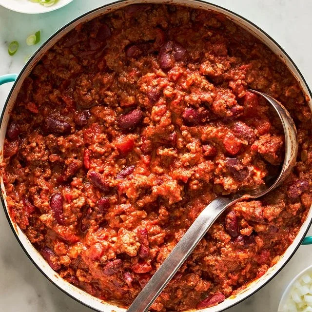 A bowl of hearty chili topped with cheese and fresh cilantro.