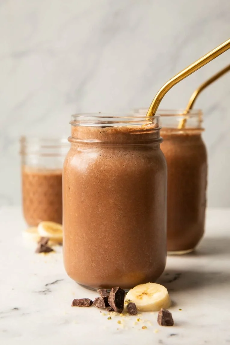 Delicious chocolate banana smoothie in a glass with fresh bananas and chocolate