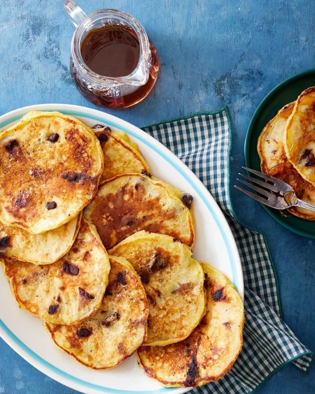 Delicious Chocolate-Clementine Pancakes stacked on a plate with fruit garnish