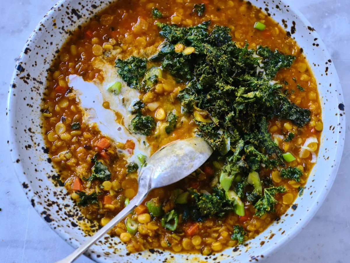 Bowl of Coconut Red Lentil Soup topped with fresh herbs