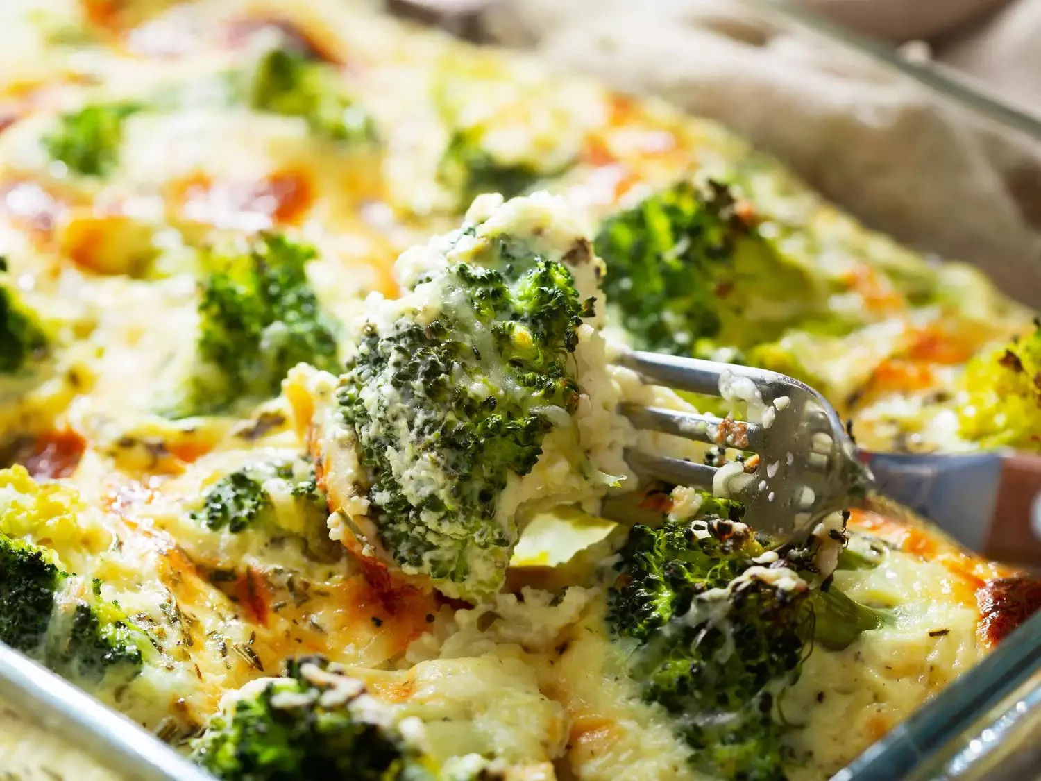 Creamy broccoli casserole with cheese and fresh broccoli in a baking dish