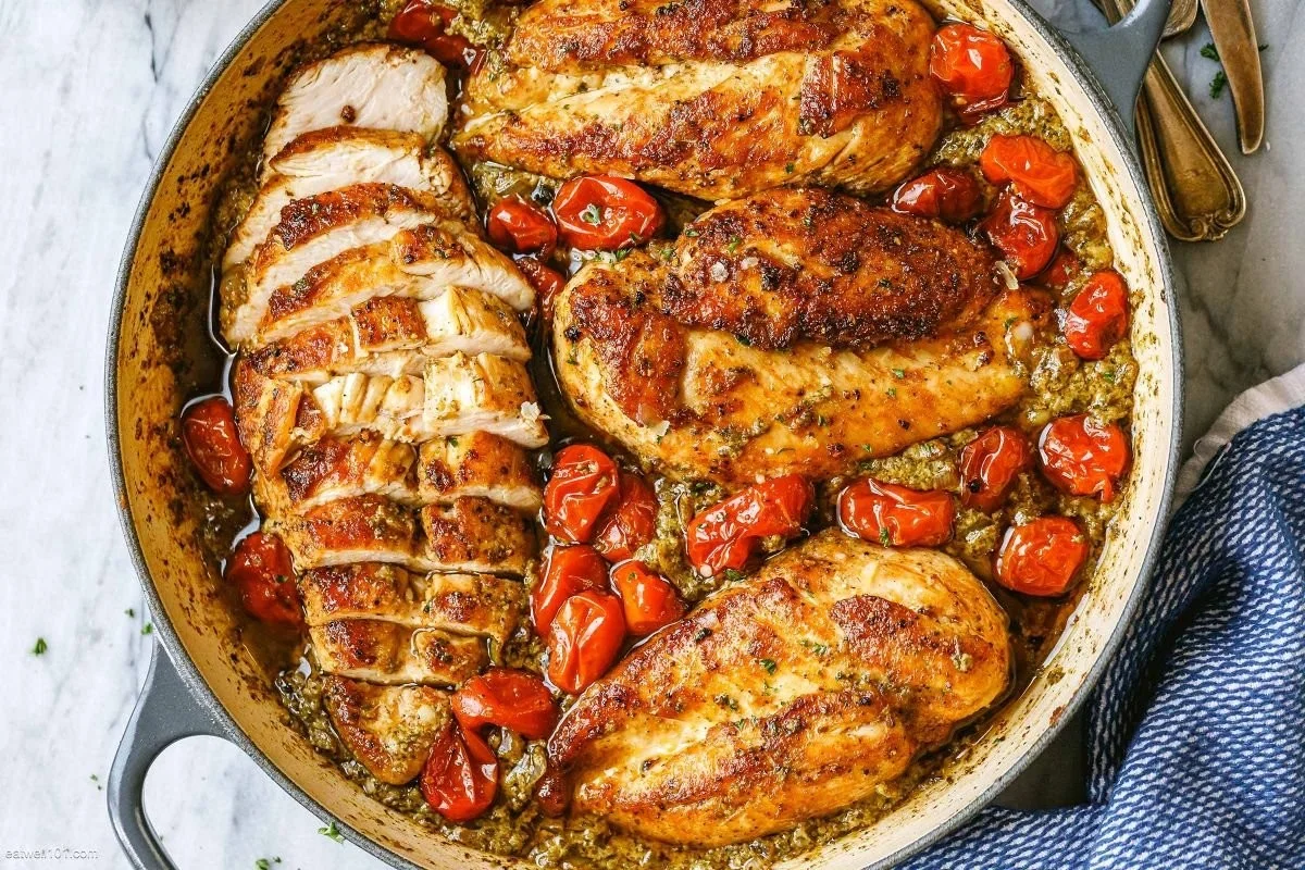 Creamy pesto chicken dish garnished with roasted tomatoes on a plate