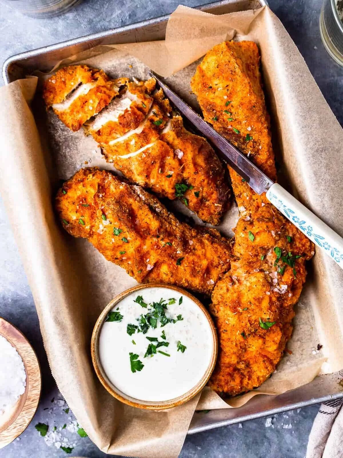 Crispy baked fried chicken served on a plate with herbs and spices.