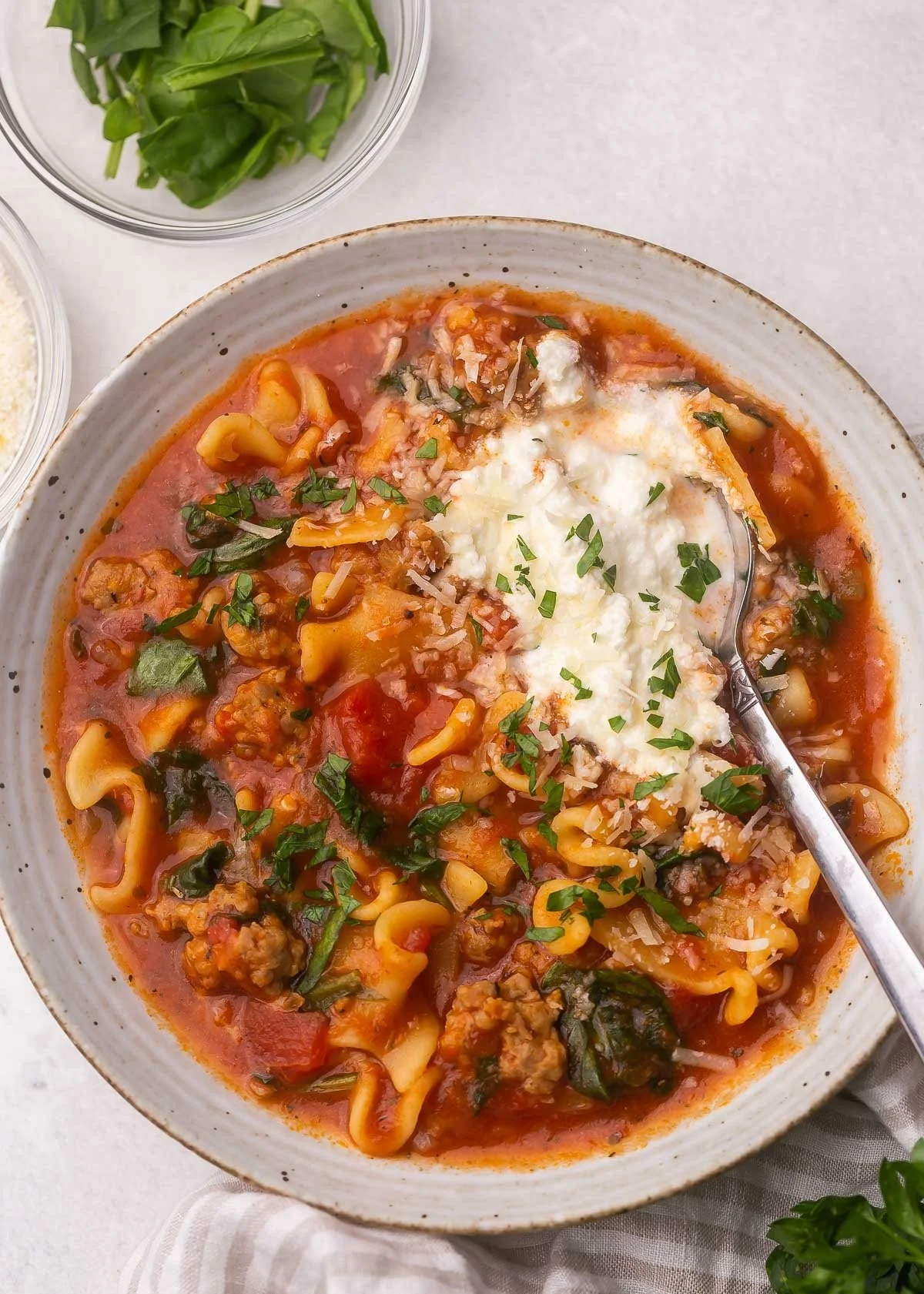 Delicious bowl of Crockpot Lasagna Soup garnished with herbs and cheese.