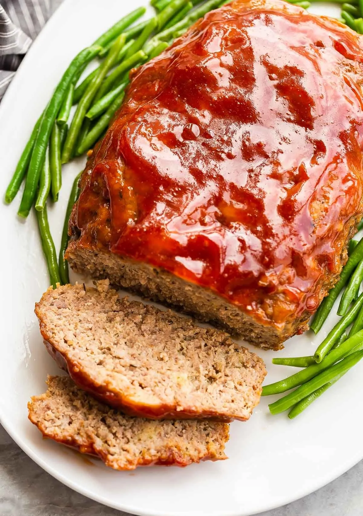 Delicious Crockpot Meatloaf served on a plate with mashed potatoes and garnish.